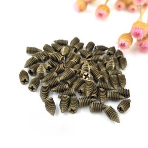 Può includere: Un grande mucchio di piccole viti dorate con punta appuntita e testa a croce.