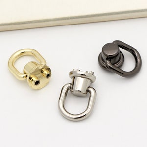 Puede incluir: Tres ganchos giratorios de metal en dorado, plateado y negro.
