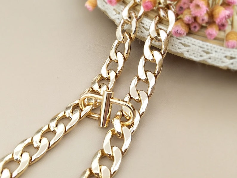 May include: A gold chain necklace with a chunky curb link design. The chain has a simple, t-bar clasp.