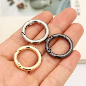 Puede incluir: Tres llaveros de metal en diferentes acabados: plateado, dorado y negro. Los anillos están abiertos y tienen un cierre de resorte.