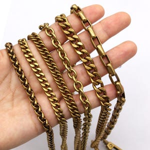 K&ouml;nnte beinhalten: Eine Hand zeigt eine Auswahl an goldfarbenen Metallketten. Die Ketten variieren im Stil, einschlie&szlig;lich Panzer-, Seil- und Box-Link-Designs. Die Ketten sind wahrscheinlich f&uuml;r die Schmuckherstellung oder als dekorative Elemente gedacht.