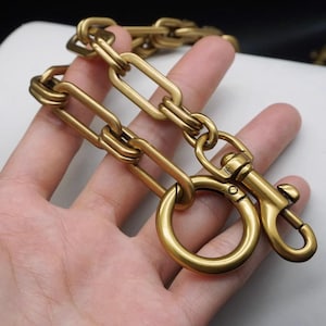 Peut inclure: Une chaîne en métal doré avec un grand motif de maillons ovales. La chaîne est munie d'un fermoir à crochet à l'extrémité.