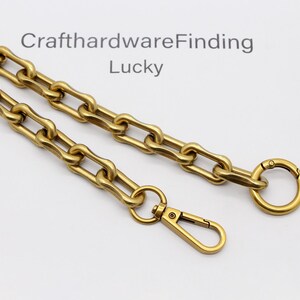 May include: A gold-colored chain with a lobster clasp and a circular clasp. The chain is made of interlocking rectangular links. The text "CrafthardwareFinding Lucky" is visible in the background.