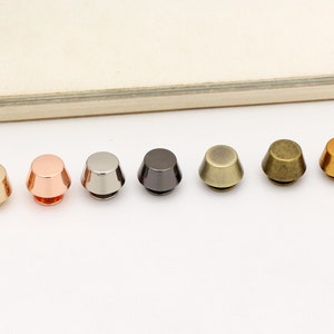 Peut inclure: Sept rivets en métal en forme de cône dans différentes finitions : argent, or rose, noir, nickel, laiton antique, or et laiton.