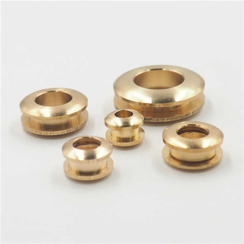 May include: Four brass grommets of different sizes. The grommets are round with a hole in the center. They are commonly used for reinforcing holes in fabric or leather.