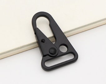 May include: Black metal clip with a spring-loaded gate and a D-ring. The clip is designed for attaching to a belt or other items.