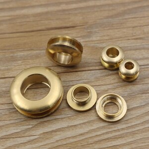 May include: A set of six brass eyelets in various sizes. The eyelets are shiny and have a smooth finish. They are ideal for adding a decorative touch to leather goods, fabric, or other materials.