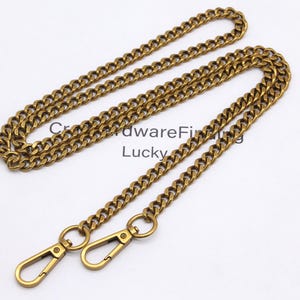 K&ouml;nnte beinhalten: Eine goldfarbene Metallkette mit zwei Karabinerhaken. Die Kette besteht aus kleinen, ineinandergreifenden Gliedern. Der Text "CrowdwareFinding Lucky" ist auf der wei&szlig;en Oberfl&auml;che darunter sichtbar.