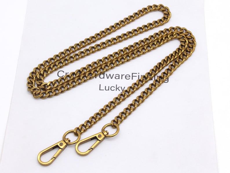 K&ouml;nnte beinhalten: Eine goldfarbene Metallkette mit zwei Karabinerhaken. Die Kette besteht aus kleinen, ineinandergreifenden Gliedern. Der Text "CrowdwareFinding Lucky" ist auf der wei&szlig;en Oberfl&auml;che darunter sichtbar.