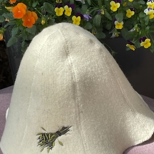 Peut inclure: Un chapeau en feutre blanc à large bord avec un motif brodé vert de tiges de blé.