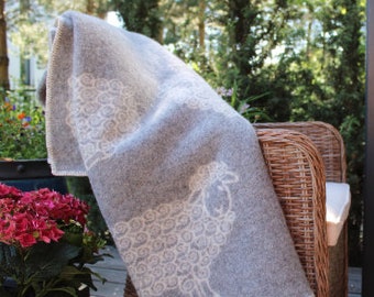 May include: A soft, gray throw blanket with a white sheep design. The sheep is made up of curly white lines.