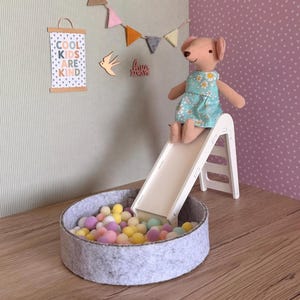 May include: A white ceramic mug with a black handle and the text "But First, Coffee" in a bold, black font. The mug is set against a blurred background, suggesting a cozy setting.