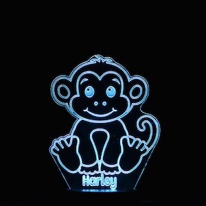 Może przedstawiać: Niebieska lampka nocna z włączonym światłem, przedstawiająca kreskówkową małpę z napisem "Harley" umieszczonym poniżej.