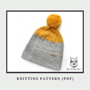 Può includere: Schema di lavoro a maglia per un berretto grigio e giallo con un pon pon. Il modello è di Holy Alpaca Knit.