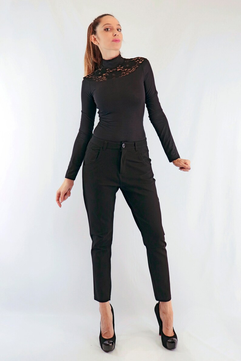 May include: A black long-sleeved top with a lace neckline paired with black trousers. The outfit is completed with black high-heeled shoes. The clothing is form-fitting and suitable for a variety of occasions.