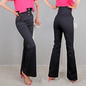 May include: Black high-waisted trousers with a flared leg design. The trousers feature a button closure and a fitted waist. The image shows the front and back of the trousers. Part of a clothing collection.