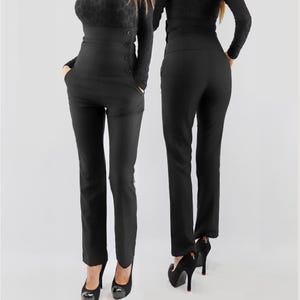 May include: Black high-waisted trousers featuring a wide waistband with three visible buttons on the side. The pants have a slim-fit silhouette, side pockets, and a straight-leg cut, shown from both the front and back views in a solid black color.