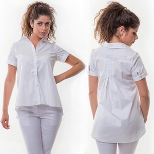 May include: A white button-down shirt with short sleeves and a slightly longer back hem.