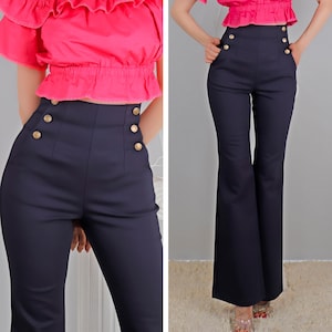 Könnte beinhalten: Eine dunkelblaue, hochgeschnittene Hose mit weitem Bein und goldenen Knöpfen. Die Hose hat ein ausgestelltes Bein und einen hohen Bund.