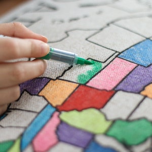 A video showing how to color your pillow sham in. Take light strokes on the top layer of the fabric. You build up the color with a light application. The example shows a hand with a green marker coloring in the state of Oklahoma.