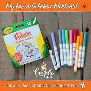 May include: A box of Crayola Fabric Fine Line Markers with a pack of 10 markers in various colors. The box features a drawing of a shirt with colorful designs. The text "My Favorite Fabric Markers!" is at the top.