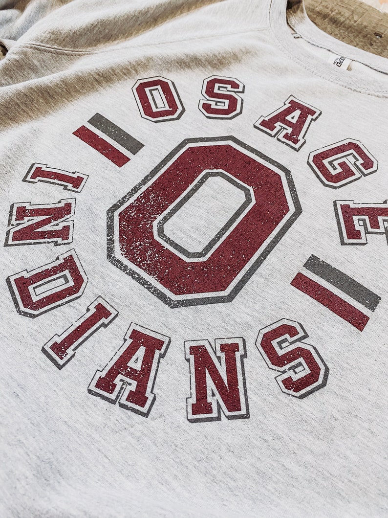 May include: Gray sweatshirt with a maroon and gray graphic that says "Osage Indians" with a large maroon "O" in the center.