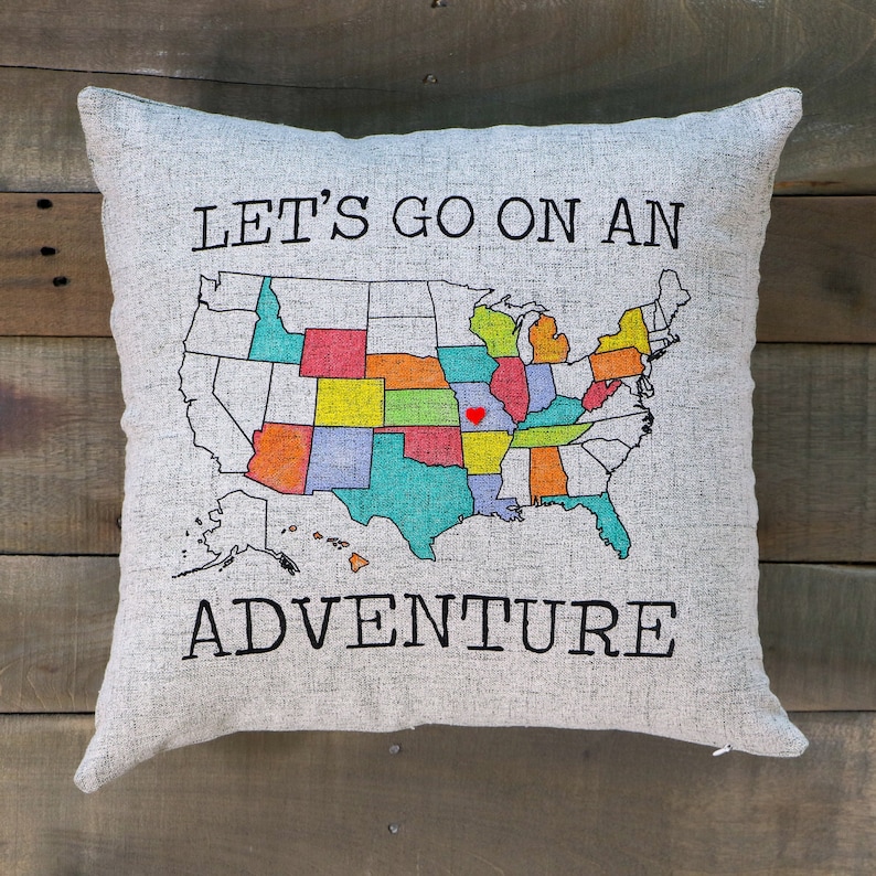 18x18 pillow sham with a zippered opening at the bottom. The sham is a soft faux linen texture and a light gray/taupe color. The front features a screen-printed US Map outline and the words Let's Go On An Adventure printed in black ink.