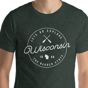 May include: A dark green t-shirt with a white circle graphic that says "Let's Go Explore Wisconsin The Badger State" with a white outline of the state of Wisconsin and two crossed paddles.