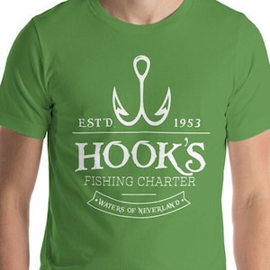 May include: A green t-shirt with a white graphic featuring a fishing hook and the text "HOOK'S FISHING CHARTER" with "ESTD. 1953" above and "WATERS OF NEVERLAND" below. The shirt is short-sleeved.