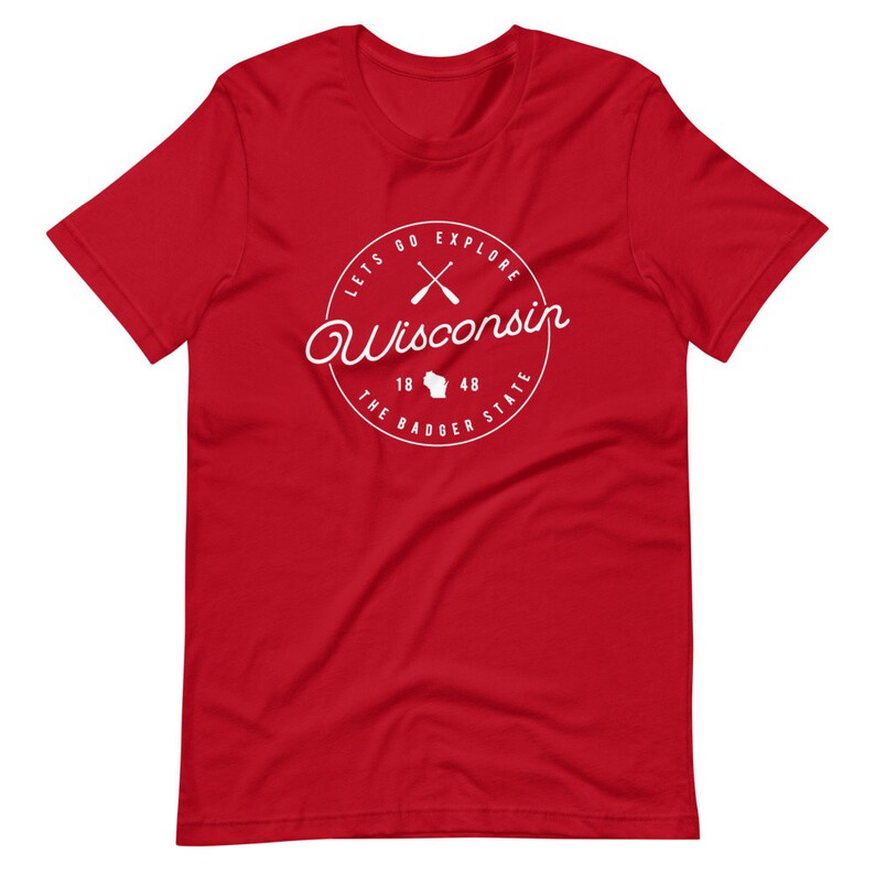 May include: Red short-sleeved t-shirt with a white circle graphic featuring the text "Lets Go Explore Wisconsin", crossed paddles, the state outline, and "The Badger State 18 48".