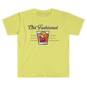 May include: Yellow t-shirt with a graphic of an Old Fashioned cocktail and the ingredients listed: 2 oz brandy, 1 splash soda, 2 dashes bitters, 1 orange slice, 1 sugar cube, 2 maraschino cherries.