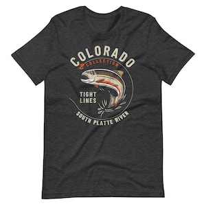 May include: A dark heather grey t-shirt with a vintage-style illustration of a trout jumping out of the water. The illustration is surrounded by a circle with the text "Colorado Collection", "Tight Lines", and "South Platte River".