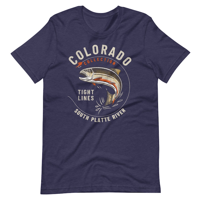 May include: A navy blue t-shirt with a white circle graphic featuring a trout jumping out of the water. The graphic also includes the text "Colorado Collection", "Tight Lines", "South Platte River".
