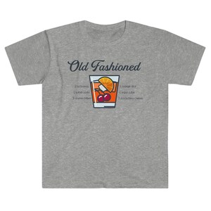 May include: A gray t-shirt with a graphic of an Old Fashioned cocktail recipe. The recipe includes 2 oz brandy, 1 splash soda, 2 dashes bitters, 1 orange slice, 1 sugar cube, and 2 maraschino cherries.