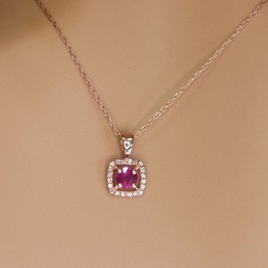 May include: A delicate rose gold necklace with a square pendant featuring a pink gemstone surrounded by smaller clear gemstones.