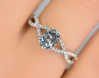 May include: A silver ring with a light blue oval gemstone set in a twisted band with small clear stones.