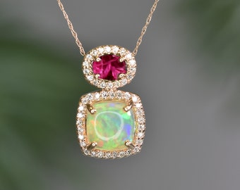 May include: A gold necklace with a pendant featuring a square-shaped opal gemstone surrounded by smaller diamonds, and a smaller round ruby gemstone surrounded by diamonds above it.