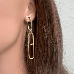 May include: Gold chain link earrings with multiple rectangular links. The earrings are long and dangle.