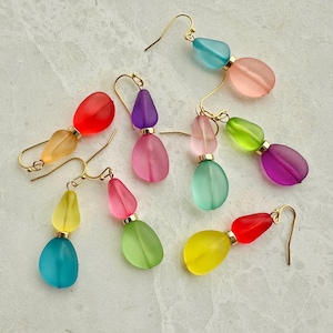 Op de afbeelding: Een set van zes paar hangende oorbellen, elk met twee druppelvormige kralen. De kralen zijn in verschillende kleuren, waaronder roze, paars, groen, blauw, geel en rood.