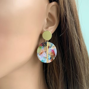 May include: Gold and multi-colored round statement earrings with a geometric design.
