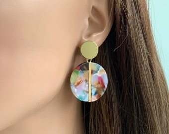 May include: Gold and multi-colored round statement earrings with a geometric design.