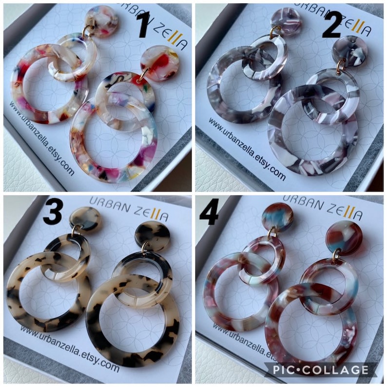 May include: Four pairs of multi-colored, layered, round, acrylic hoop earrings. Each pair is unique with different color combinations and patterns. The earrings are displayed on a white background with the text "URBAN ZELIA" and a website address.