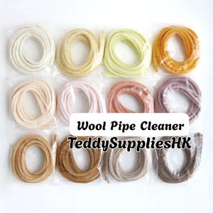 May include: A collection of twelve coiled wool pipe cleaners in various colors, including white, yellow, pink, orange, brown, and grey, each individually wrapped in clear plastic. The text Wool Pipe Cleaner TeddySuppliesHK is visible.