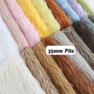 Könnte beinhalten: Eine Sammlung von Kunstfell-Stoffmustern, die in parallelen Reihen angeordnet sind und eine vielfältige Farbpalette mit Weiß, Rosa, Gelb, Braun, Blau und Grau aufweisen. Jeder Stoff hat eine lange, weiche Textur mit einer Florhöhe von 35mm.