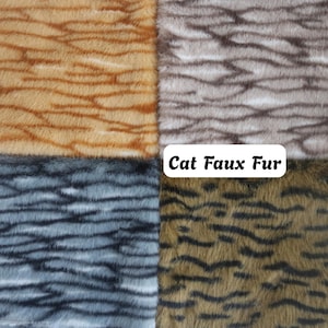 May include: Four swatches of faux fur fabric arranged in a grid, each featuring a distinct animal-inspired pattern. The colours include orange, grey, blue-grey, and olive green, all with dark horizontal stripes. A white label reads Cat Faux Fur.