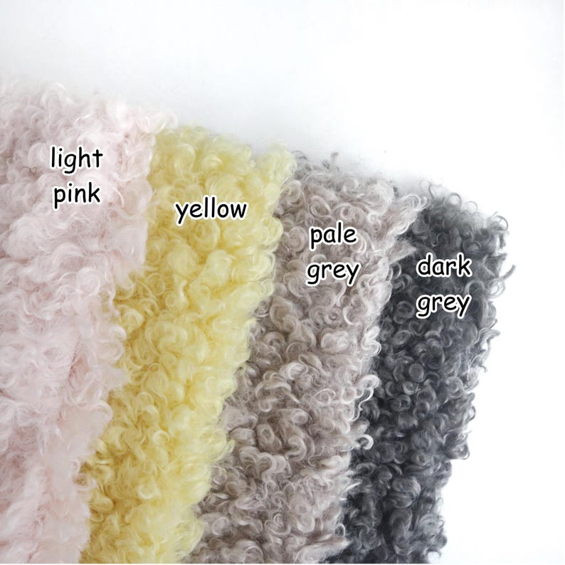 May include: Four swatches of curly, textured fabric arranged side by side. The colors from left to right are labeled light pink, yellow, pale grey, and dark grey. Each section features a dense, looped pile surface with a consistent, uniform texture.