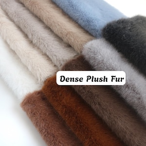 May include: A collection of folded fabric swatches featuring dense plush fur in various colors including white, beige, light blue, dark brown, grey, and black. A white rectangular label with the black text Dense Plush Fur is visible.