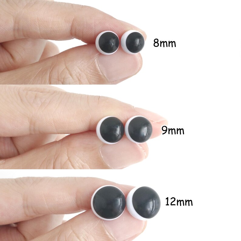Op de afbeelding: Drie paar ronde, zwart-witte plastic veiligheidsogen voor knutselwerk, getoond in de maten 8mm, 9mm en 12mm. Elk paar heeft een effen zwarte pupil gecentreerd op een witte basis, gepresenteerd in een helder overzicht voor maatvergelijking.