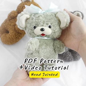 Könnte beinhalten: Ein salbeigrüner Plüschbär mit einer hellblauen Schleife am Kopf und Hals, schwarzen Augen, einer schwarzen Nase und einem roten Mund. Der Text lautet: PDF Pattern + Video Tutorial, Head Jointed. Der Bär hat eine flauschige Oberfläche.