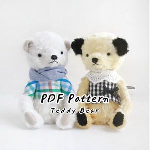 May include: Two plush teddy bears, one white and one cream with black ears, wearing miniature clothing. The white bear wears a blue scarf and plaid shirt, while the cream bear wears a white lace collar and black gingham top. Text reads: PDF Pattern Teddy Bear.